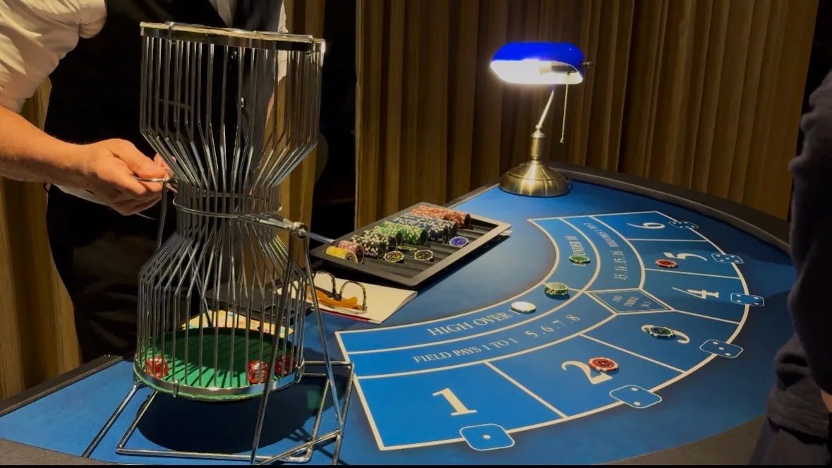 Croupier faisant tourner la cage à dés du Chuck-a-Luck pendant la soirée à Disneyland Paris