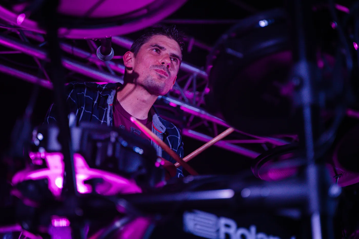 Batteur du groupe éclairé en violet et magenta pendant le concert