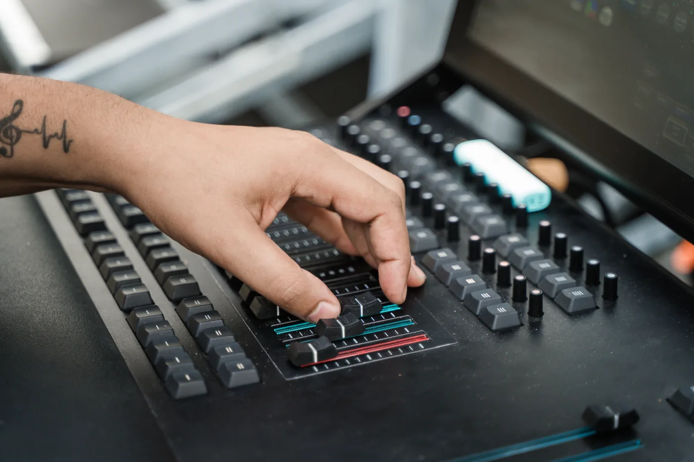 Main du technicien sur la console lumière pendant le pilotage du concert en direct