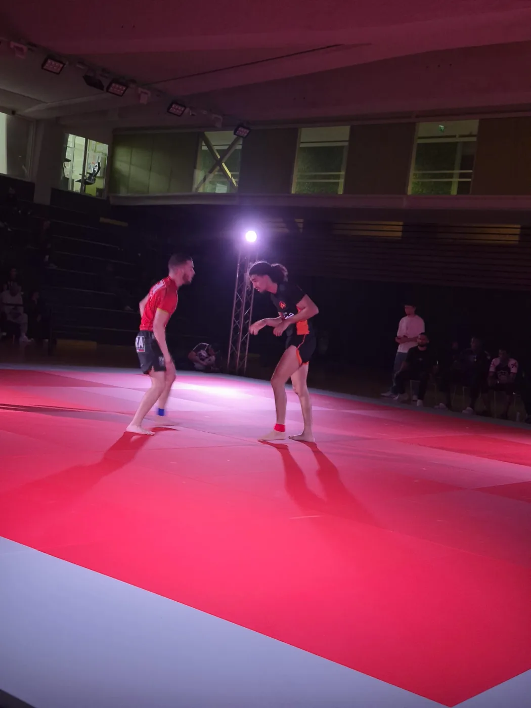 Deux combattantes sur le tapis, sous la mise en lumière scénique installée pour la compétition