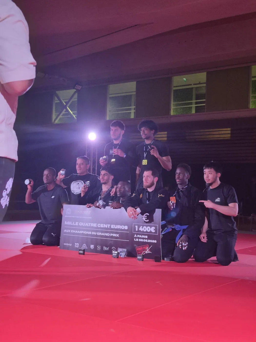 Séance photo des vainqueurs à la fin de la soirée, aire de combat éclairée en rose