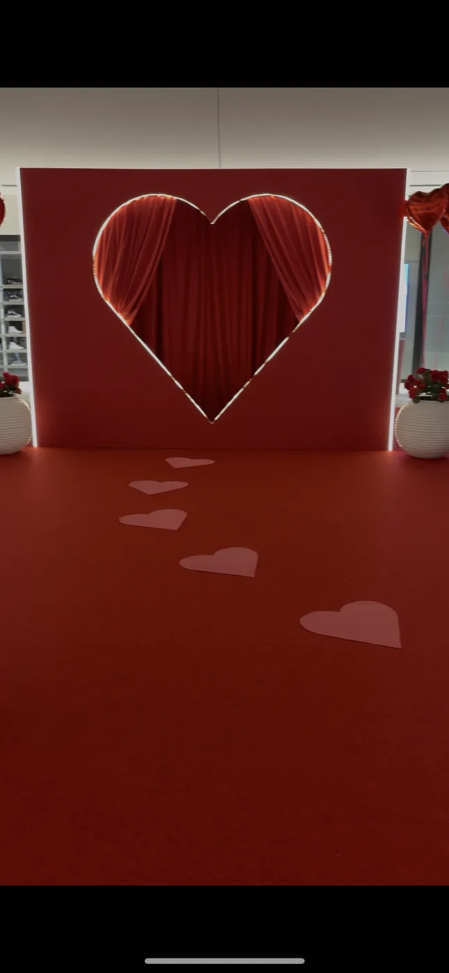 Photocall en forme de cœur souligné d'un néon, drapé rouge au centre et cœurs posés sur la moquette