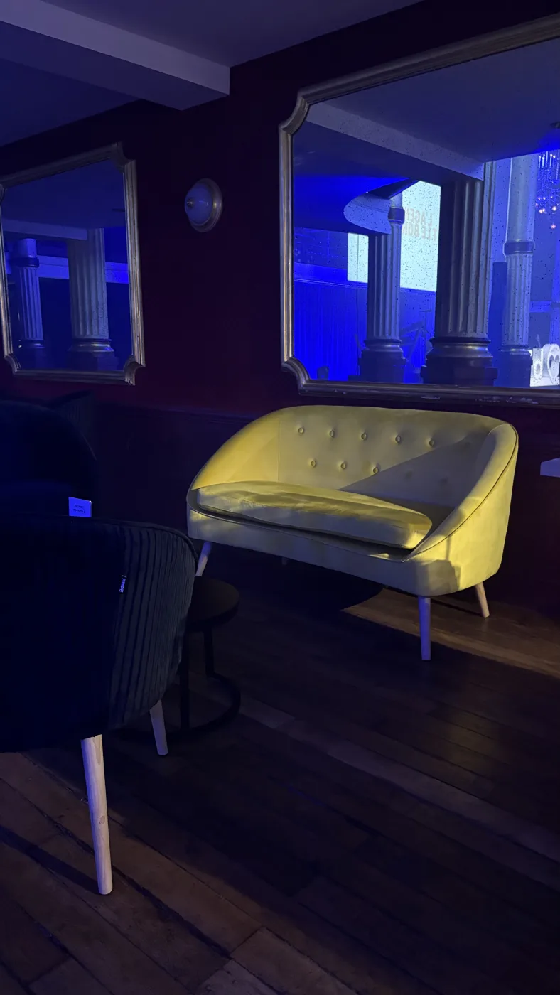 Canapé jaune deux places et fauteuils noirs en velours installés dans un salon du Pavillon Wagram