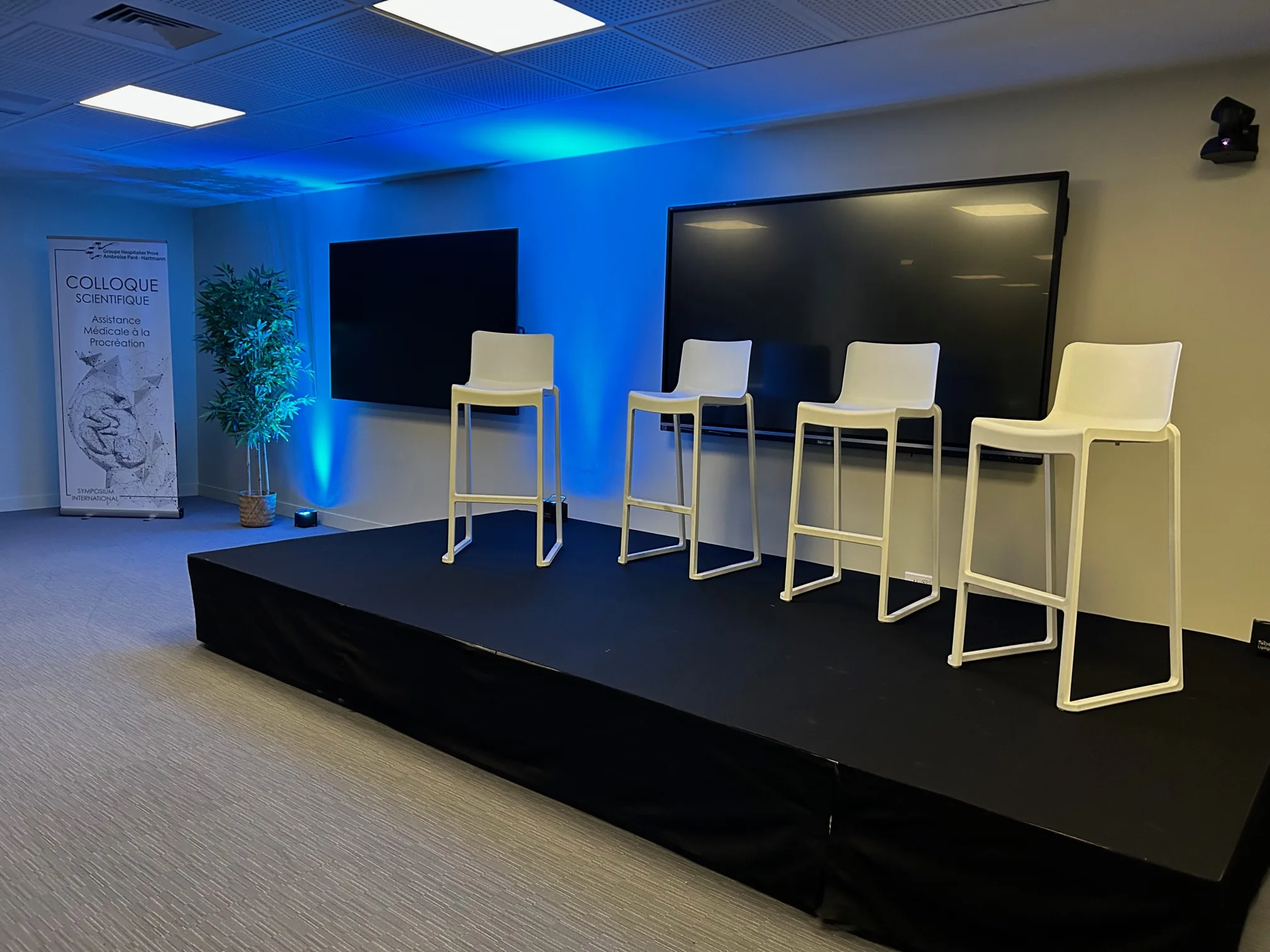 Salle de colloque équipée : estrade, écrans et assises hautes