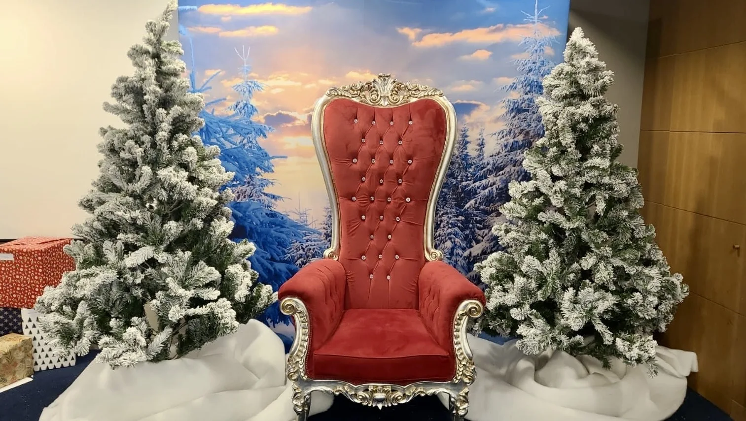 Décor de Noël posé dans un hall : sapins enneigés et fauteuil rouge